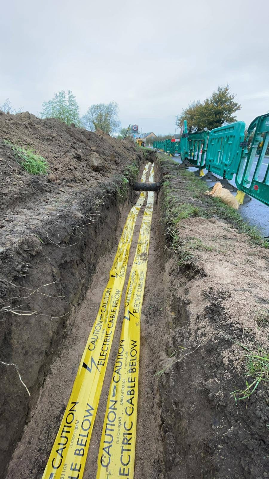 Roadside trench with yellow electric cable warning tape